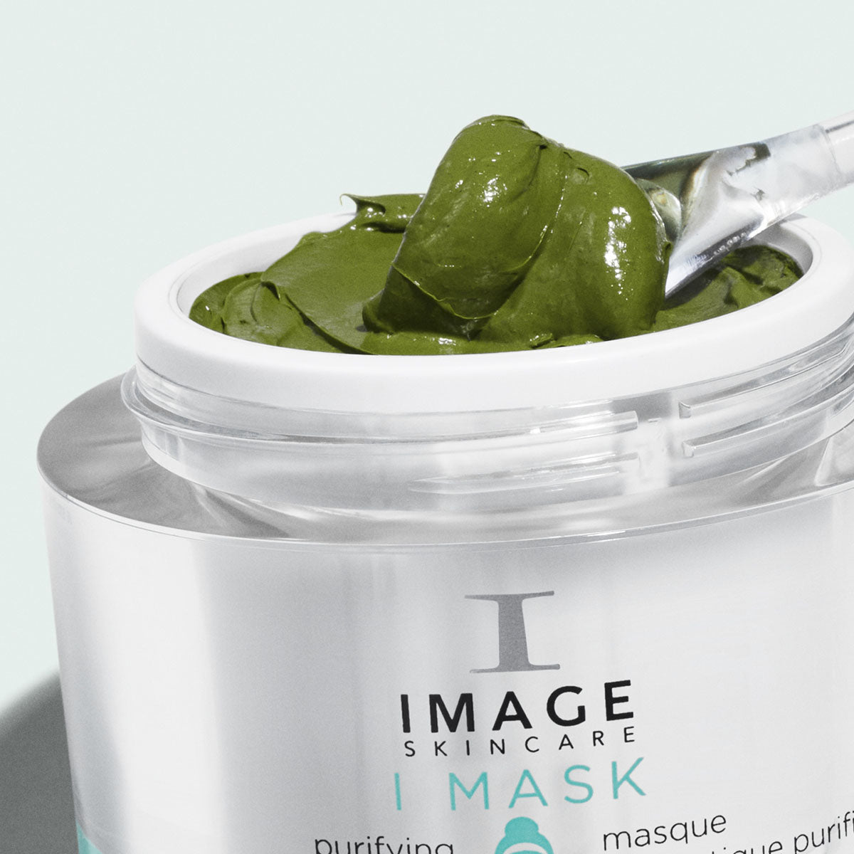 open jar of probiotic mask with green product being scooped out