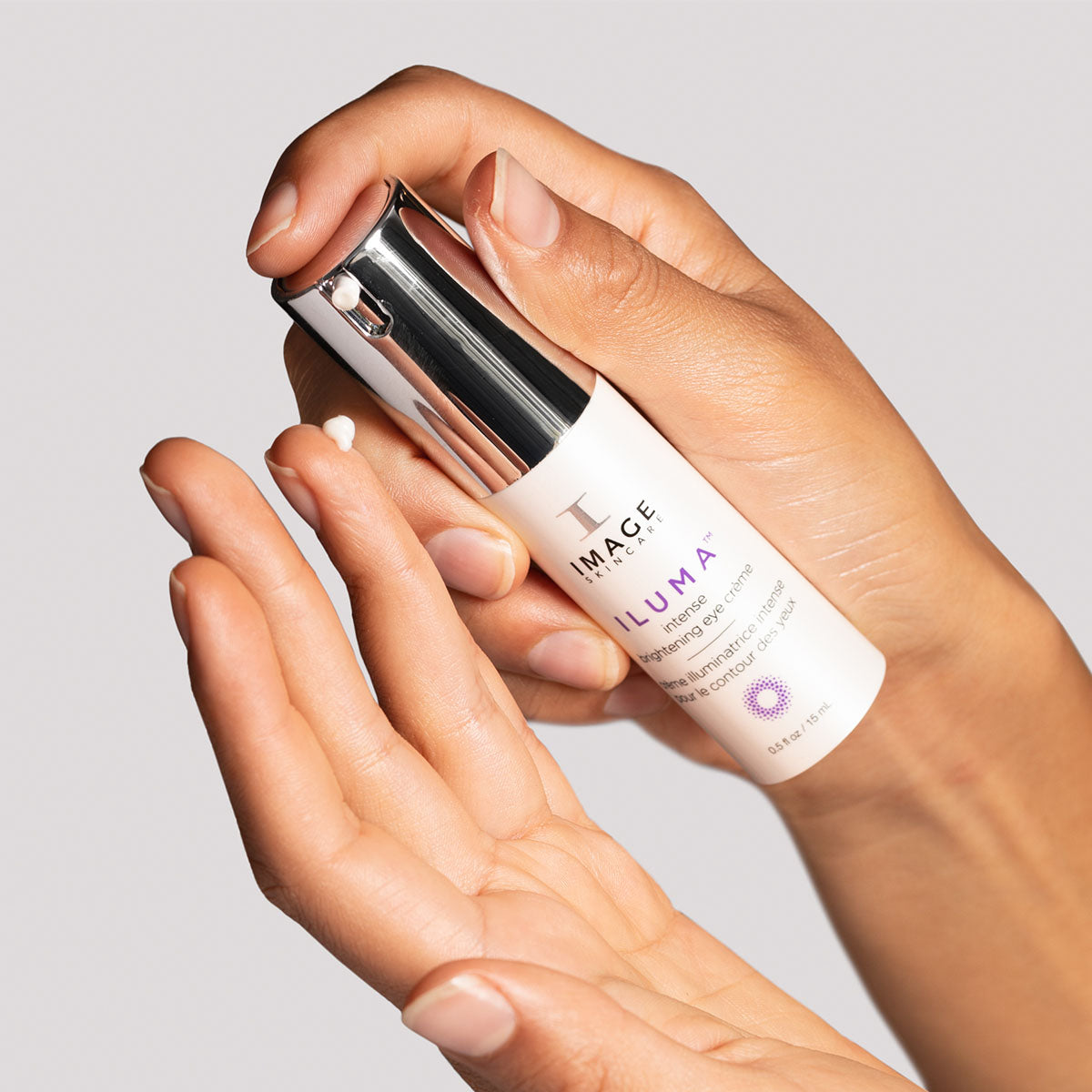 model hands dispensing iluma eye creme onto finger