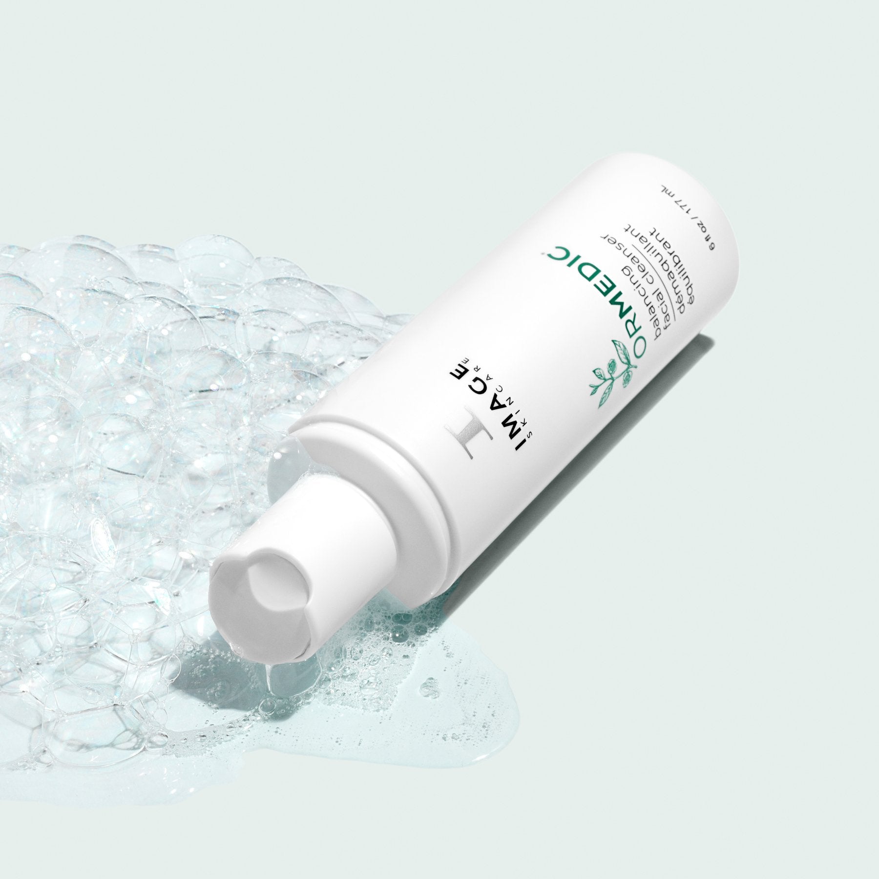 ormedic cleanser bottle opened with cleanser and bubbles pouring out on light background