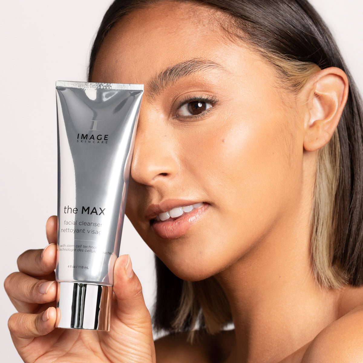 model holding tube of MAX cleanser close to face