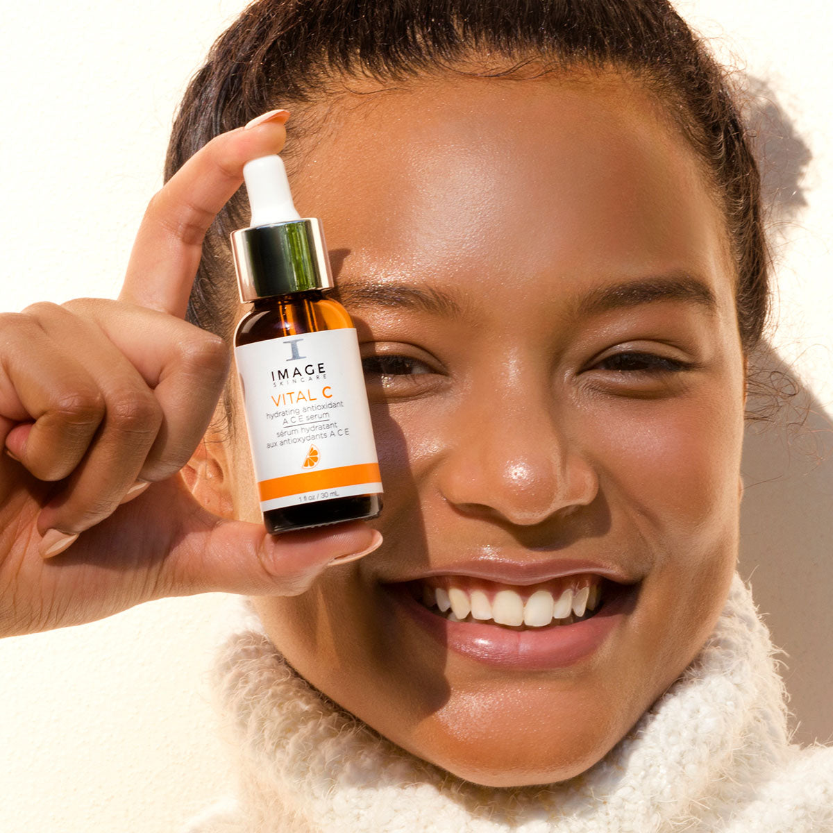 model wearing white, smiling holding ACE bottle close to face
