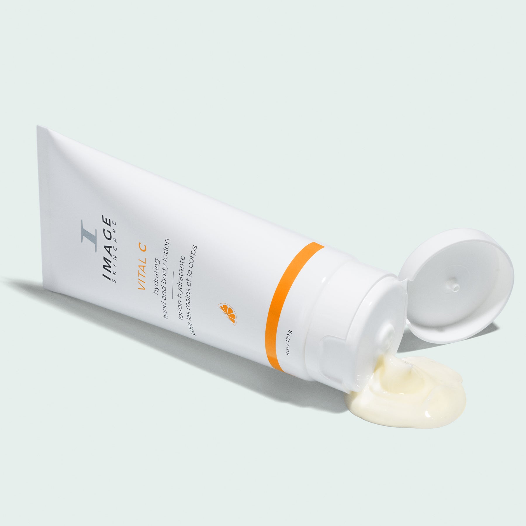 vital c lotion bottle open on a mint background with product coming out of bottle